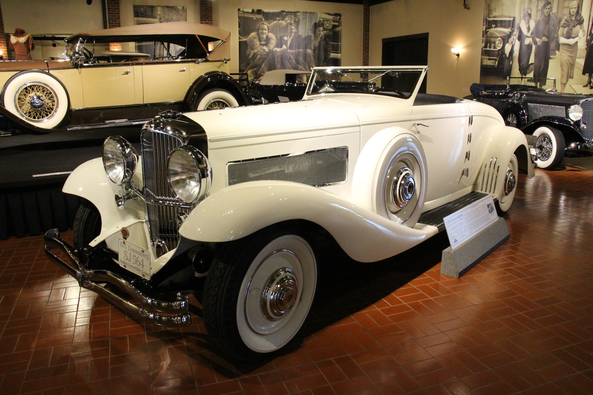 White 1935 Duesenberg Model JN supercharged cabriolet displayed in a museum gallery