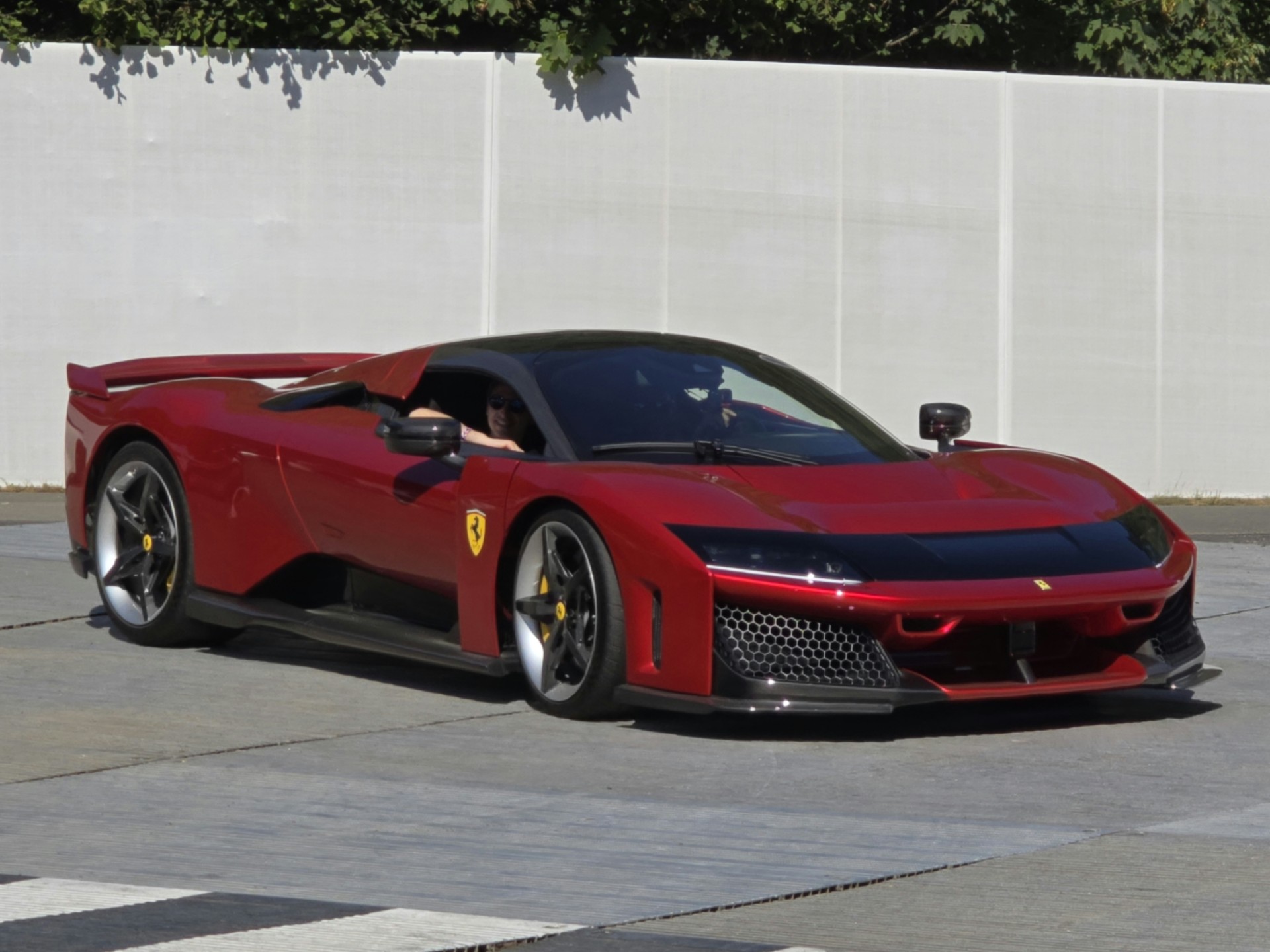 Red Ferrari F80 hybrid hypercar in front three-quarter view on the road