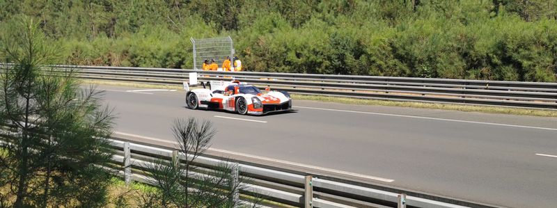 Red and white Toyota GR010 Hybrid race car speeding on the Le Mans circuit
