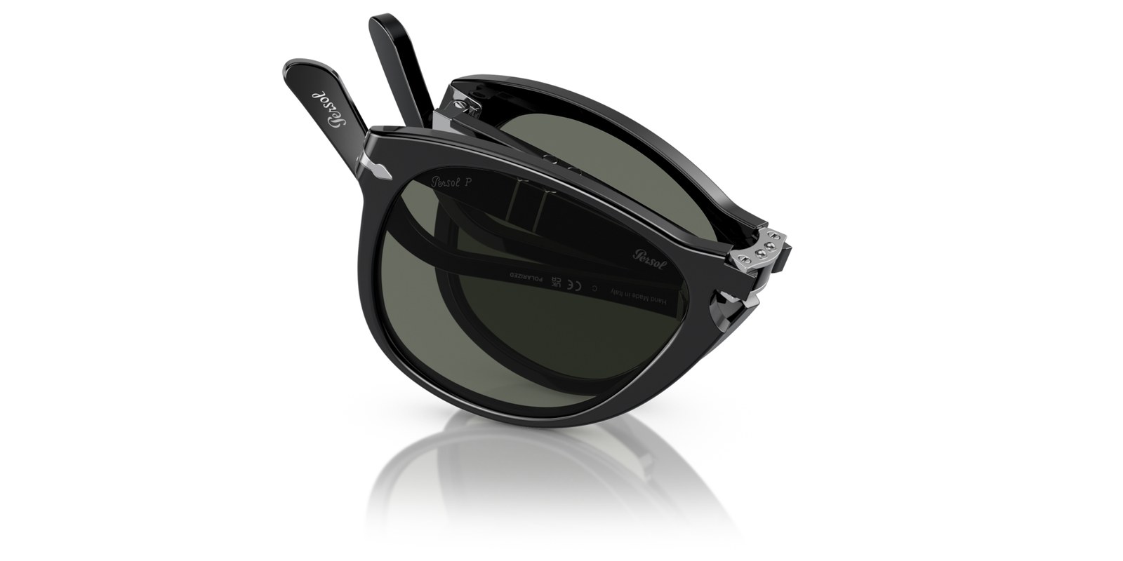 The Persol 714 folding sunglasses in black acetate with green lenses, photographed in three-quarter view showing the pilot shape, keyhole bridge and folding temples
