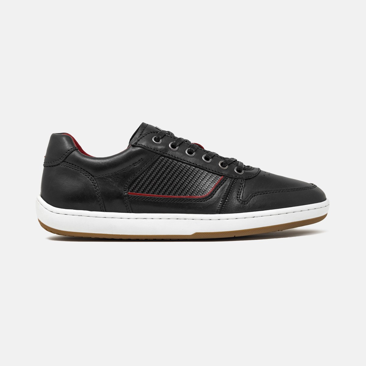 A single black Piloti Compass driving shoe photographed in three-quarter profile on a light studio background, showing the low-profile sneaker silhouette, leather panels and the curved Roll Control heel